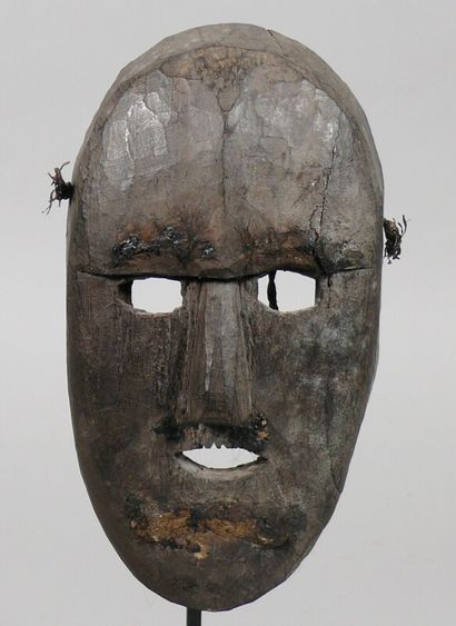 null Hardwood mask with a dark patina of use depicting a geometrical oval face with...