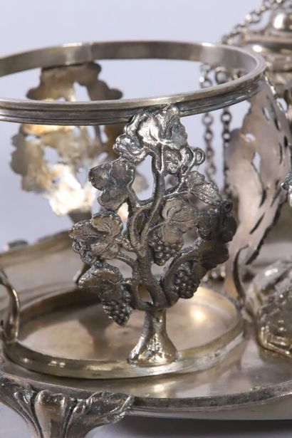 null Oil cruet in silver with scrolls. The bottle holders decorated with vine stocks.
The...