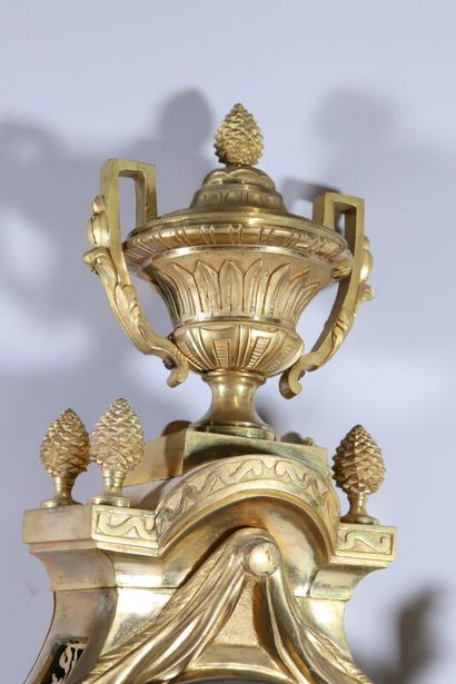 null Gilt bronze and chased cartel, topped by a covered vase and pine cones
The white...
