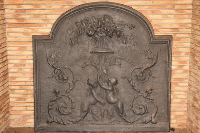 null Cast iron fireback decorated with putti supporting a vase of flowers in foliage
H....