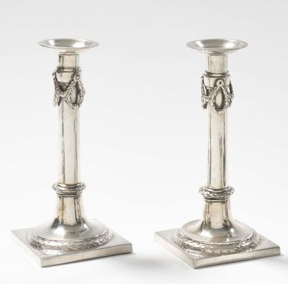 null Pair of plain silver torches resting on a square base, underlined with laurel...