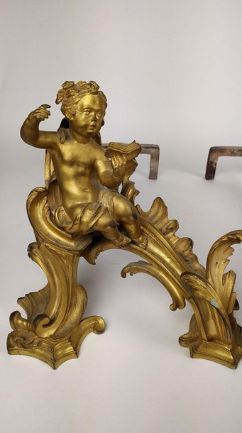 null PAIR OF CHENETS in chiselled gilt bronze with a musical putto and a reading...