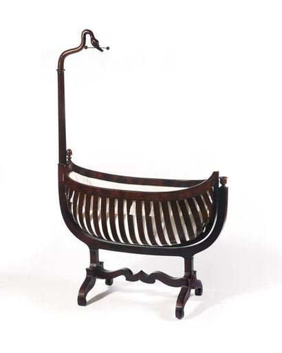 null A mahogany and mahogany veneer cradle, with a gooseneck upright, it rests on...