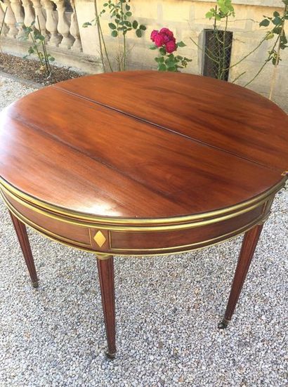 null GAME TABLE in mahogany half-moon with a brass ring, opening on the top by two...