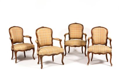 null A suite of four moulded and sculpted beechwood armchairs with rounded convertible...