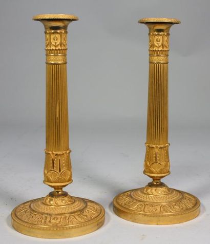 null * PAIRE de BOUGEOIRS en forme de colonne en bronze ciselé et doré orné de cannelures,...