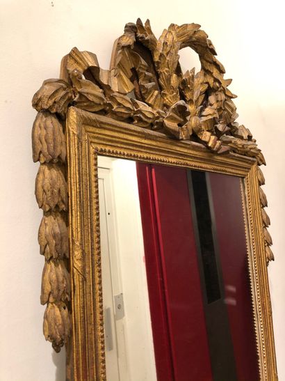 null FRONT MIRROR in gilded wood molded and carved with a ribboned frieze and a frieze...