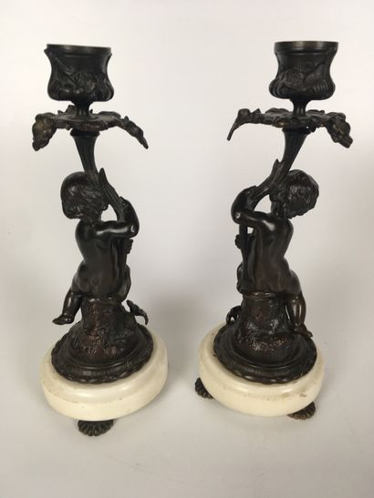 null Pair of candlesticks in patinated bronze with putto decorations hung on branches....