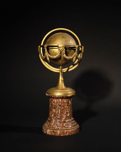 null A brass and ormolu SPHERE decorated with garlands and mascarons, standing on...