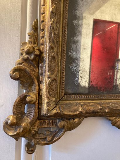 null A giltwood FRONTIER MIRROR, molded and carved with foliage and shells, the engraved...