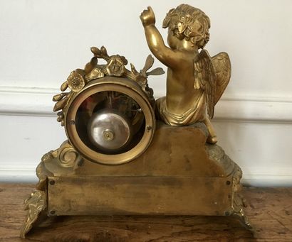 null An ormolu and chased clock decorated with a cherub sitting on a mound playing...