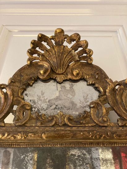 null A giltwood FRONTIER MIRROR, molded and carved with foliage and shells, the engraved...