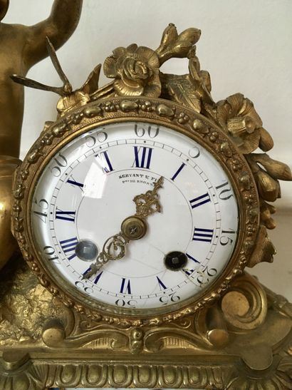 null An ormolu and chased clock decorated with a cherub sitting on a mound playing...