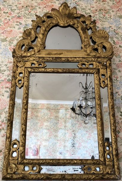 null A gilded wood mirror with moulded and carved lambrequins and decorated with...