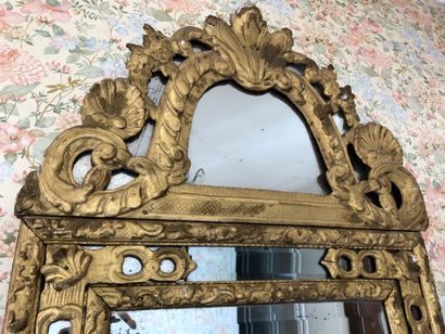 null A gilded wood mirror with moulded and carved lambrequins and decorated with...