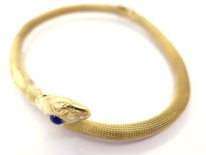 null BRACELET in 14K yellow gold representing a coiled snake holding a cabochon sapphire...
