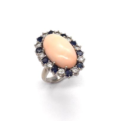 null RING presenting an oval angel-skin coral cabochon in a setting of brilliant-cut...