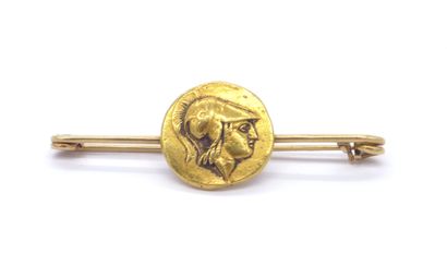  18K yellow gold brooch holding a coin displaying engravings of a minerve in profile...