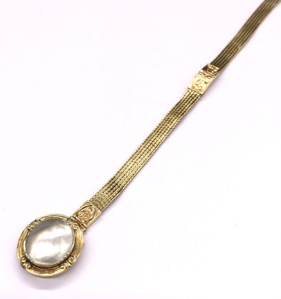  BRACELET retenant une perle blanche ovale cerclée d'une monture en or jaune au dessin...