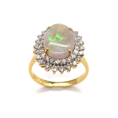  BAGUE présentant une opale blanche dans un double entourage de diamants taille brillant....