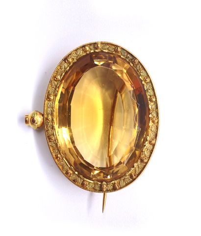 A large yellow citrine in a brooch. The setting...
