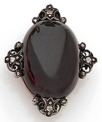 null A cabochon of pyrope garnet with a vegetal design at the ends, studded with...