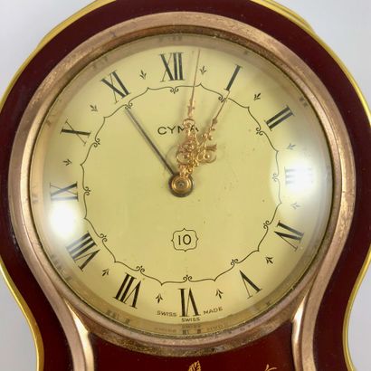 null CYMA CLOCK. Dial decorated with a floral motif. Alarm function. Roman numeral...