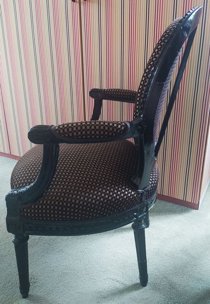 null A black lacquered wood medallion back armchair resting on four tapered legs...