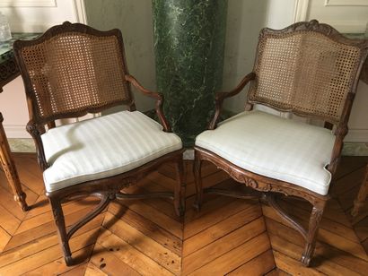  A PAIR OF ARMCHAIRS with a curved back, in natural wood, moulded and carved with...