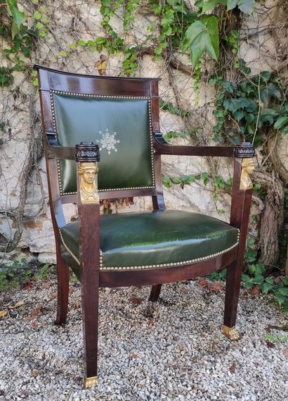 null A mahogany desk chair with straight back, the armrests with caryatid busts,...