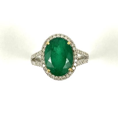 null RING holding an oval emerald of approximately 4.80 carats in a brilliant-cut...