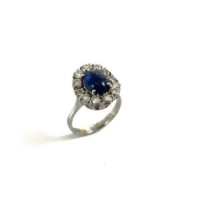 null RING adorned with a sapphire cabochon in a circle of brilliant-cut diamonds....