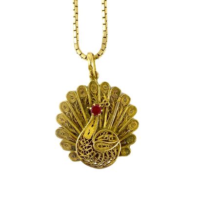 null PENDANT decorated with a peacock filigree holding a red stone. It is accompanied...