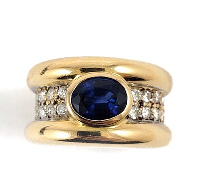 null RING adorned with three gadroons, the main one holding an oval sapphire set...