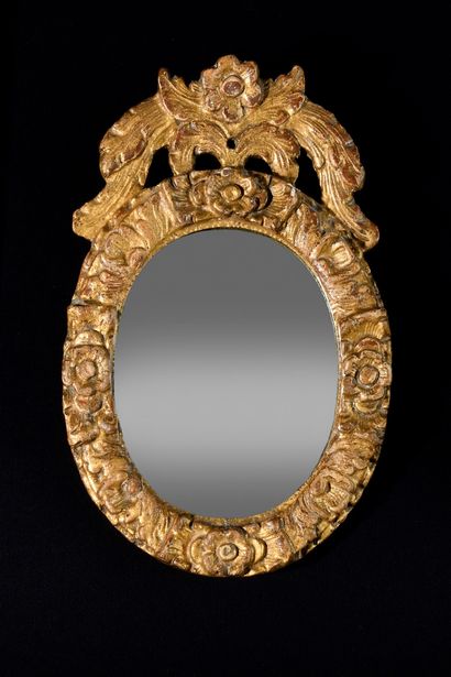 null SMALL OVAL MIRROR in wood carved with flowers and volutes. XVIIIth century Height....