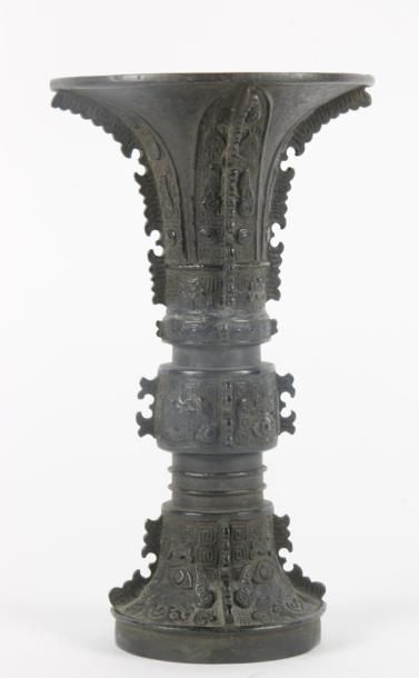 CHINE - XIXe siècle Vase de forme "gu" en bronze à patine brune à décor de masques...