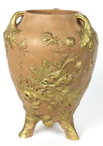 J. DUQUET Vase en terre cuite rehaussé or à motif végétal reposant sur trois patins....