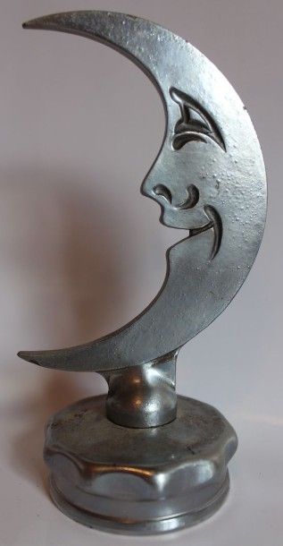 null “Lune qui rit”
Mascotte en métal chromé. 
Montée sur bouchon. 
H: 13 cm.