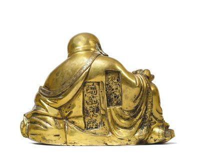 CHINE Bouddha souriant assis sur une rocaille en bronze doré tenant d’une main une...