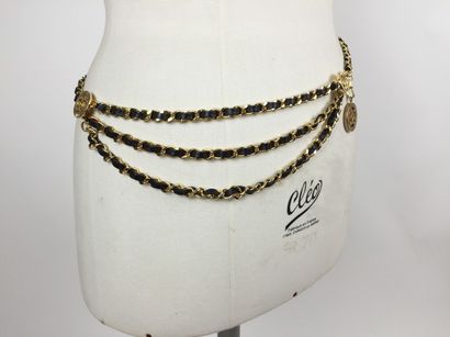 CHANEL CEINTURE en trois chaînes en métal doré entrelacée de cuir noir. Décorée de...