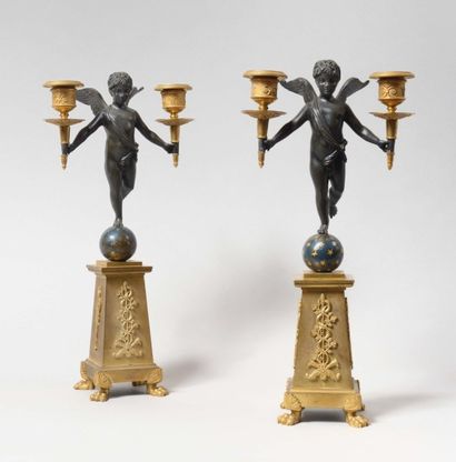  Paire de candélabres en bronze patiné et doré représentant un putto ailé tenant...