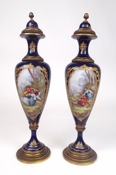 null SEVRES (dans le goût de) Deux vases fuseaux à fond bleu décoré en polychromie...