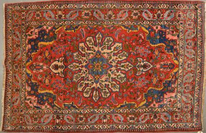 null Tapis d'Orient en laine à décor de fleurs sur fond rouge et d'un motif central...