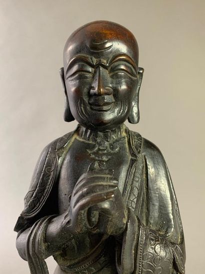 null Bouddha en bronze ciselé et patiné noir debout sur une fleur de lotus. 
Chine,...