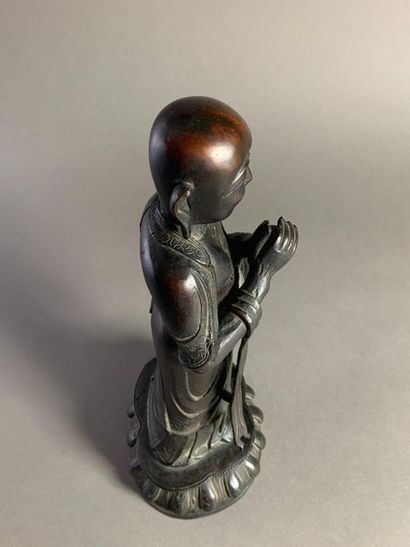 null Bouddha en bronze ciselé et patiné noir debout sur une fleur de lotus. 
Chine,...
