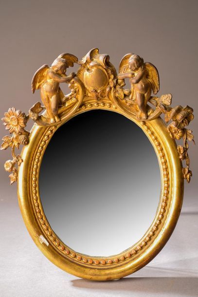 null Petit miroir ovale à fronton en bois sculpté, stuqué et doré, surmonté d'un...
