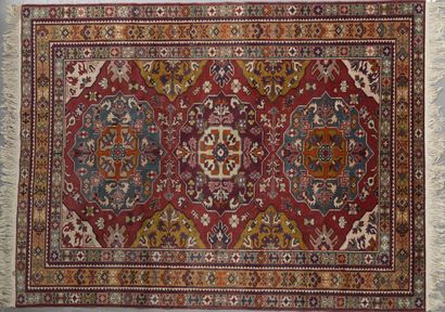 null Woollen rug with a red background centred on three central medallions and polychrome...