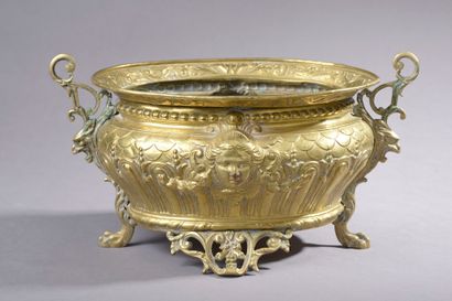 null Oval planter in embossed brass, the body centered with masks on a background...