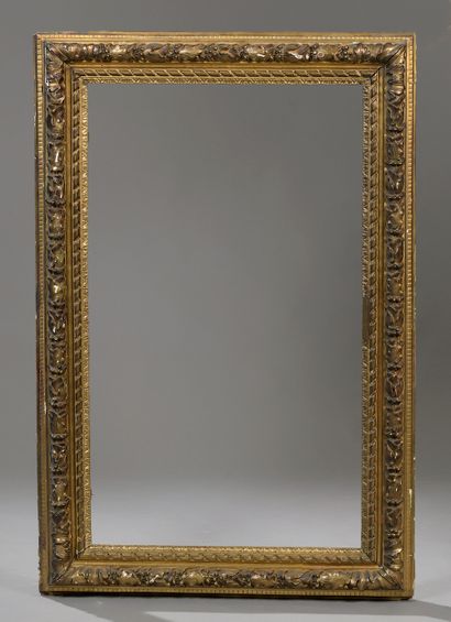  A large rectangular frame in carved wood, stuccoed and gilded, decorated with foliage...
