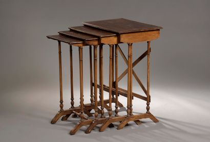 Four stained walnut nesting tables, the rectangular...